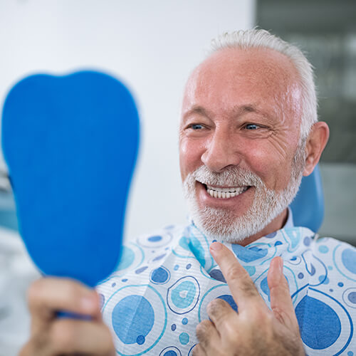 Image of a senior man smiling into a mirror